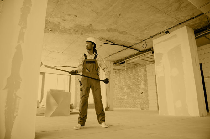 Construction worker painting wall with roller in building under construction